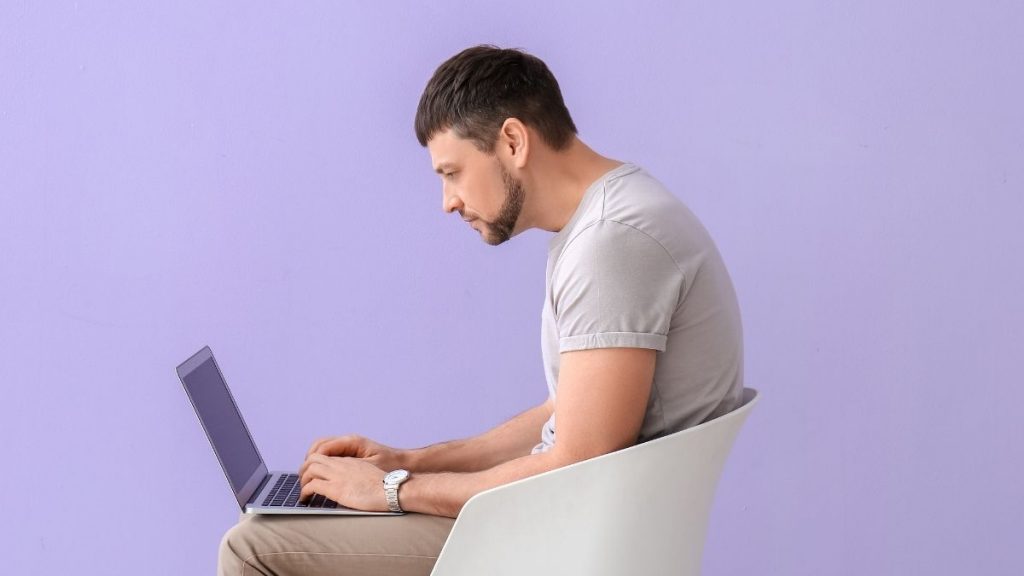 rounded shoulder posture demonstrated by a man using a laptop