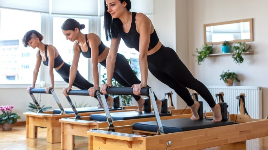 3 ladies doing Pilates reformer long stretch exercise