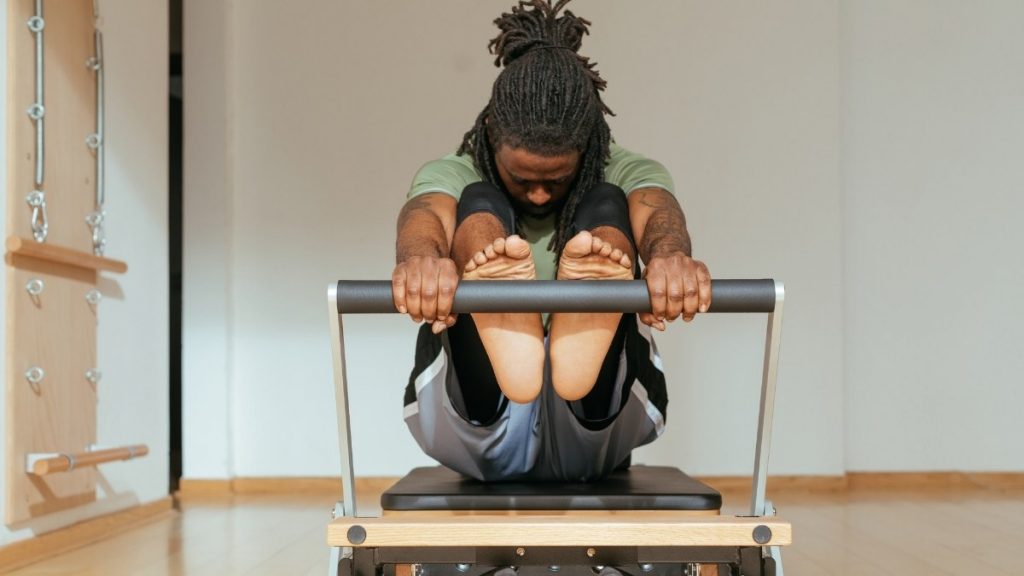 a man stretching his hamstrings on the Pilates reformer
